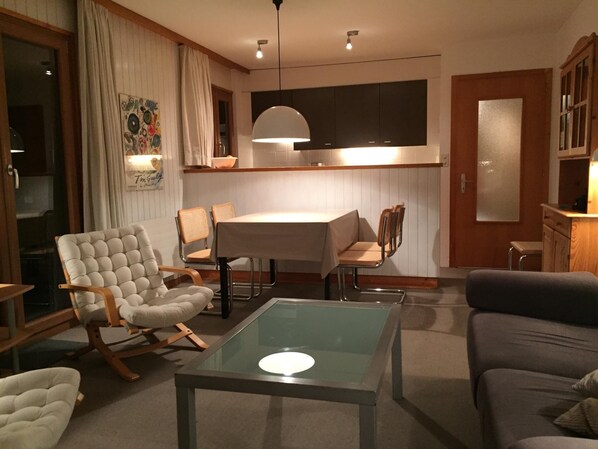 Un salon moderne avec une table basse en verre, un canapé et un coin repas comprenant une table et des chaises.