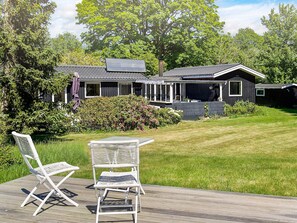 A house with a deck, two white chairs, and a garden. - 8 Person Holiday Home in Asnaes (Asnaes)