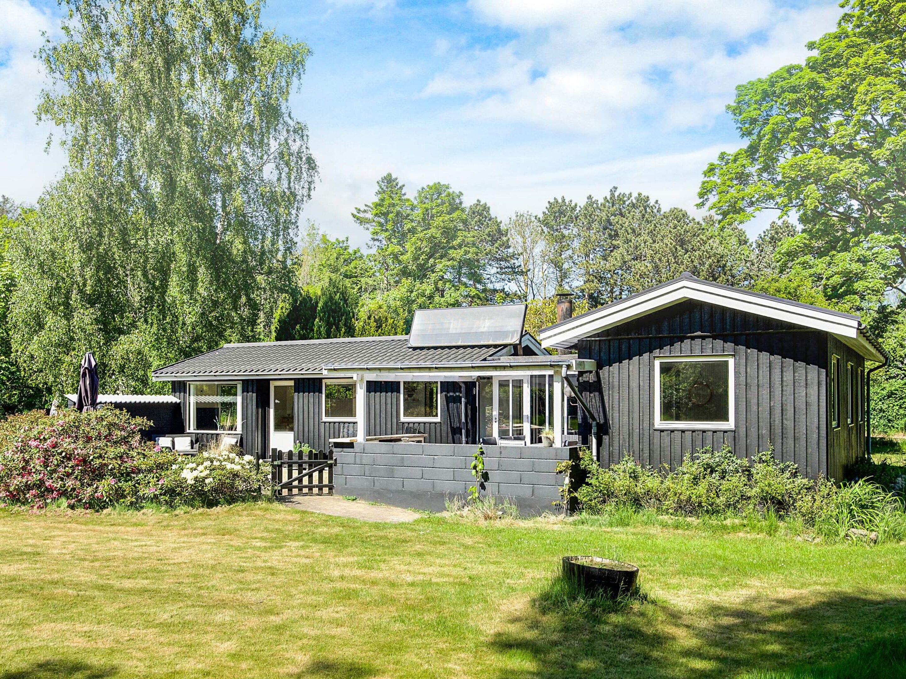 A modern house with a covered patio, a small shed, and a lawn.
