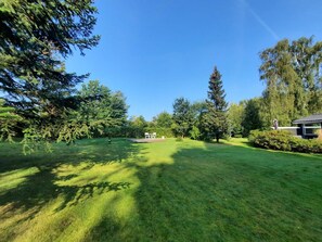 A well-maintained grassy area with trees, a statue, and a building in the background. - 8 Person Holiday Home in Asnaes (Asnaes)