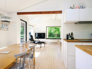 A modern kitchen with white cabinetry, a wooden countertop, and a large window with a view of greenery. - 8 Person Holiday Home in Asnaes (Asnaes)