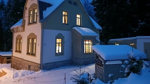 Una casa de dos pisos con techo nevado y garaje.