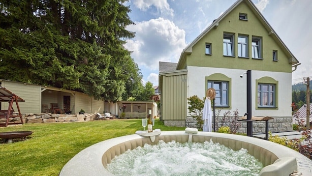 Un jacuzzi en un patio trasero, con una casa al fondo.