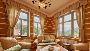 Una habitación acogedora tipo cabaña de madera, con paredes de madera, ventanas amplias y una mesa de madera en el centro.