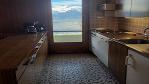 Una cucina con vista su montagne innevate attraverso una porta.
