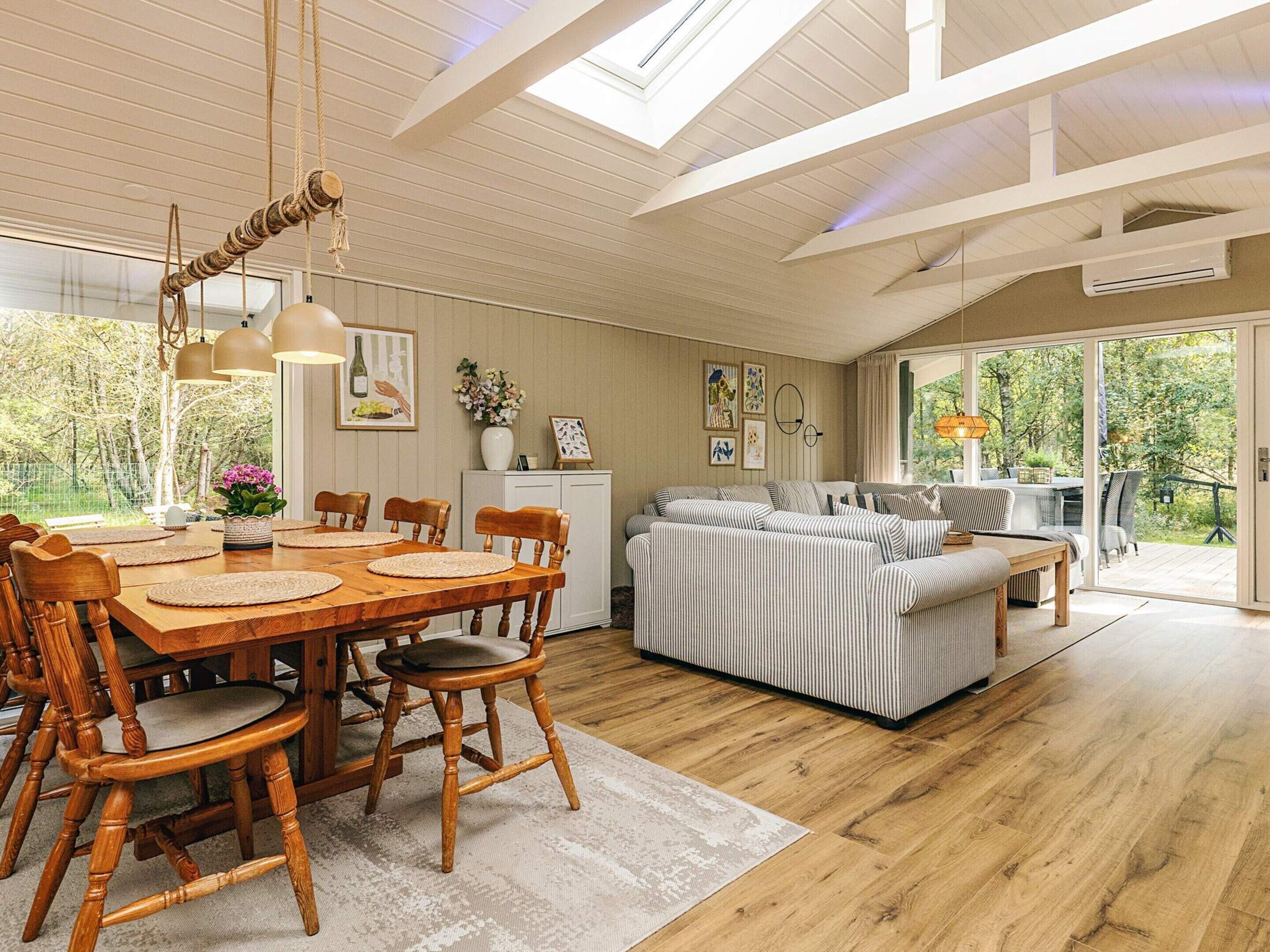 Een ruime woonkamer met een houten eettafel, stoelen en een bank.