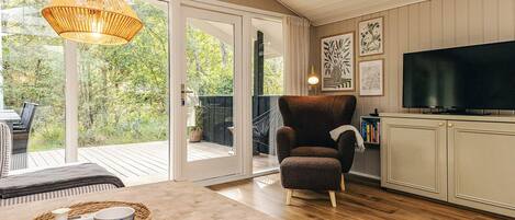 A room with a wooden floor, a sofa, a television, and a large window.