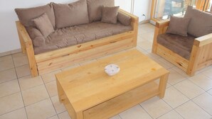 Eine Holz-Sofagarnitur mit passendem Couchtisch in einem Raum mit Fliesenboden.