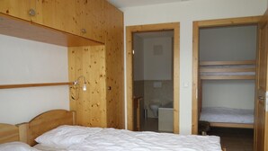 Ein Schlafzimmer mit einem Holzstockbett, einem Einzelbett und einem Schrank aus Holz.