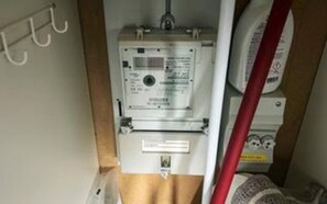 Contador de utilidades com etiqueta, cano vermelho e parede branca.