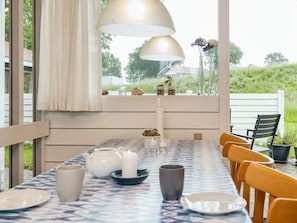 An outdoor dining area with a table set for two, featuring a patterned tablecloth, white plates, a teapot, candles, and a vase with flowers. - 5 Person Holiday Home in Aabenraa (Aabenraa)