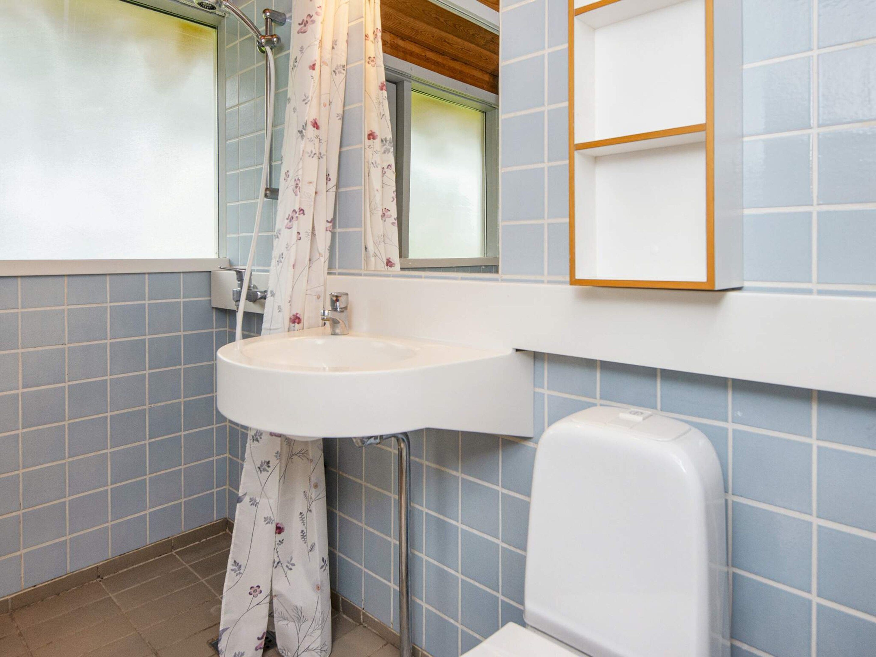 A bathroom with a white sink, a shower with a floral curtain, and a toilet.