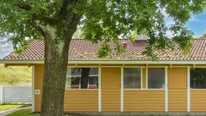A single-story building with a tiled roof, a large tree in front, and a grassy lawn. - 5 Person Holiday Home in Aabenraa (Aabenraa)