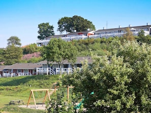 A hotel with multiple-story buildings, a playground with swings and a slide, and a picnic table in the foreground. - 5 Person Holiday Home in Aabenraa (Aabenraa)