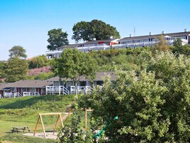 A hotel with multiple-story buildings, a playground with swings and a slide, and a picnic table in the foreground.