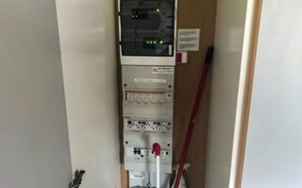 Painel de controle com vários interruptores e indicadores, uma placa com texto e um poste vermelho.