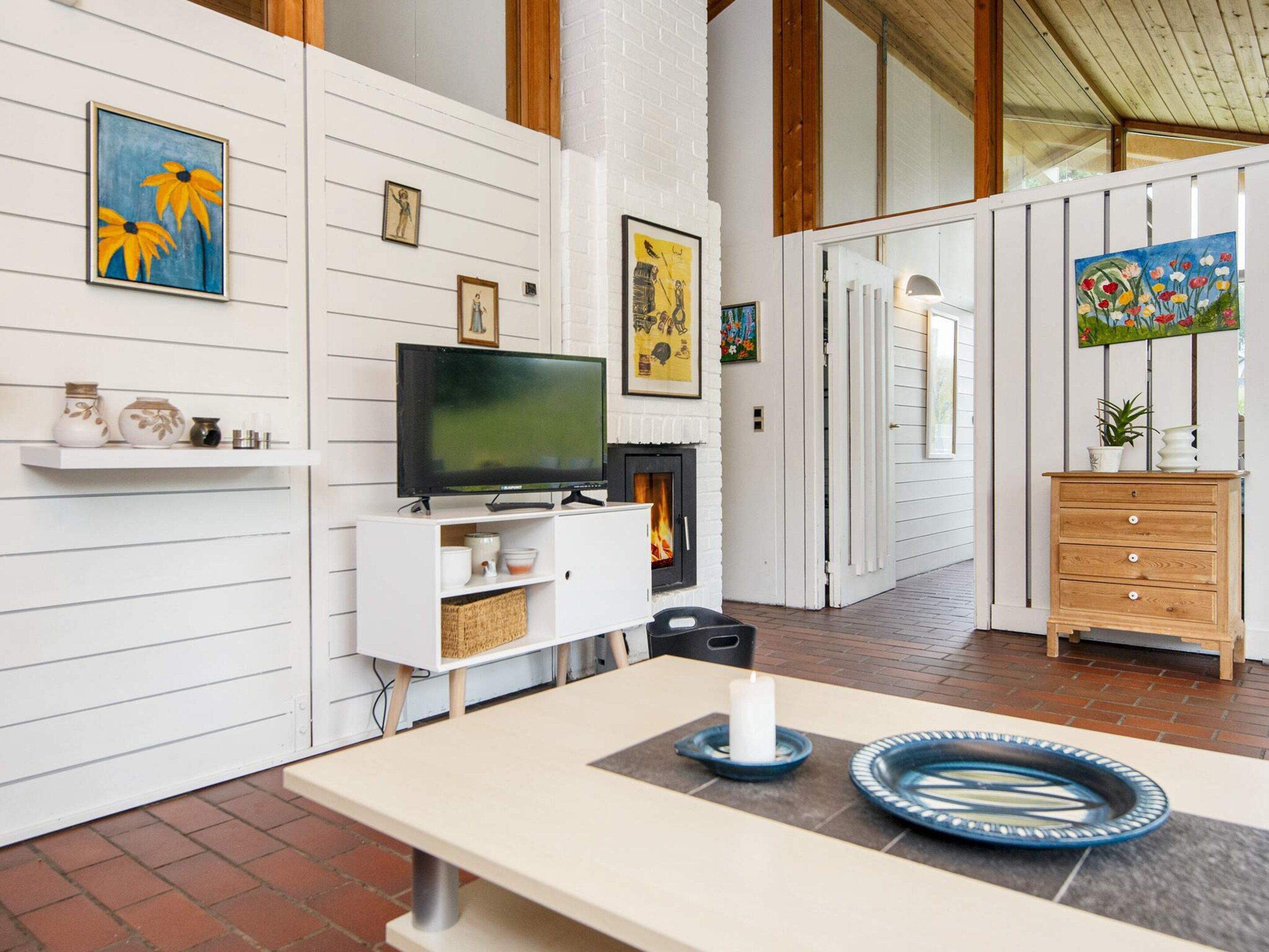 Una sala de estar moderna con chimenea, televisión y comedor.