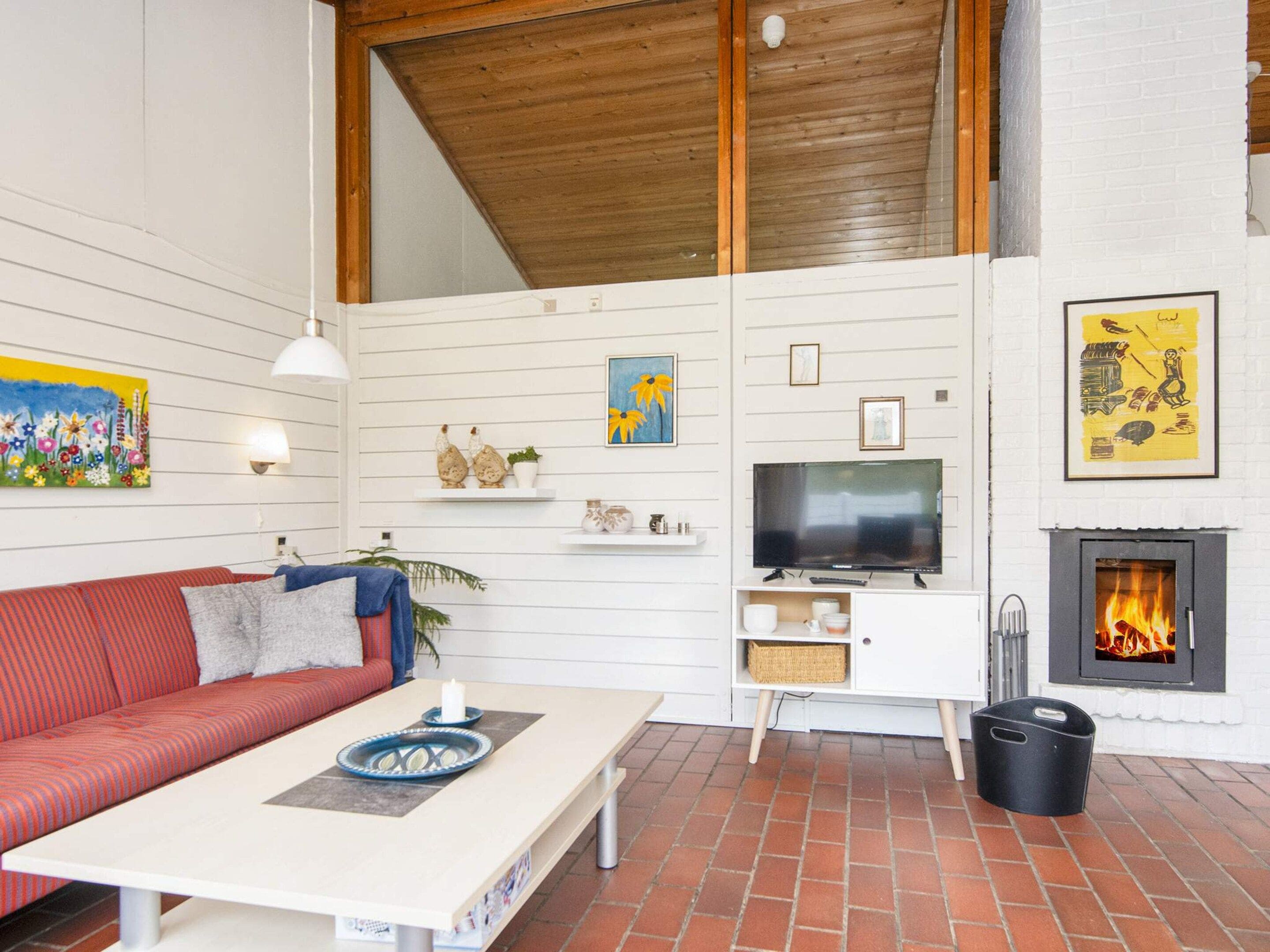 A living room with a red sofa, a white coffee table, a television, and a fireplace.