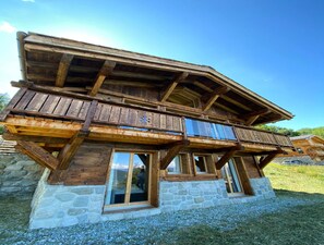 A wooden chalet with a stone base, multiple balconies, and large windows. - Bishorn Cosy Chalet 4 Personnes (Vex)