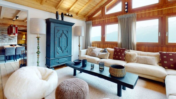 Ein gemütliches Wohnzimmer mit Holzboden, einer Sofagarnitur, einem Schrank und einem Essbereich mit Stühlen und Tisch.