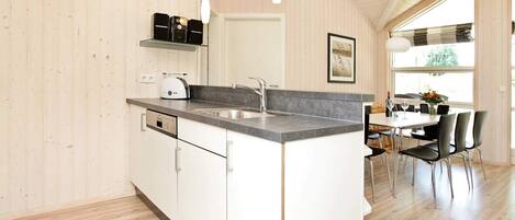 A modern kitchen with a built-in island, white cabinetry, and a large window providing natural light.