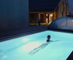 Ein Schwimmbad bei Nacht, in dem eine Person schwimmt.