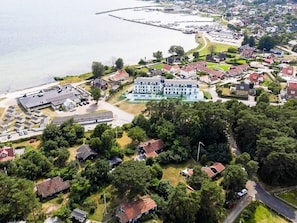 Vista aérea de una zona residencial con casas, un edificio grande de techo plano y una masa de agua.