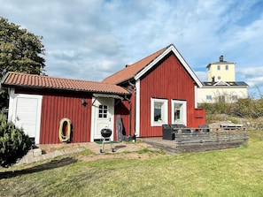 A red wooden house with a white door, a garage, and a small porch area. - 4 Person Holiday Home in Figeholm (Figeholm)