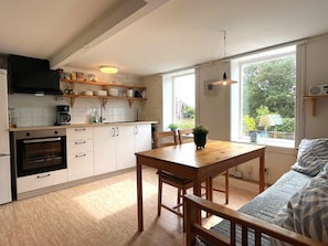 A modern kitchen with white cabinets, a built-in oven, and a dining area with a wooden table and chairs. - 4 Person Holiday Home in Figeholm (Figeholm)