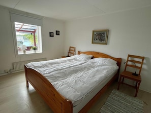A bedroom with a wooden bed, a window with a view, a radiator, and a small table. - 4 Person Holiday Home in Figeholm (Figeholm)