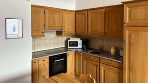 A kitchen with wooden cabinets, a microwave, and a sink. - Pleasant Apartment With Balcony (Veysonnaz)