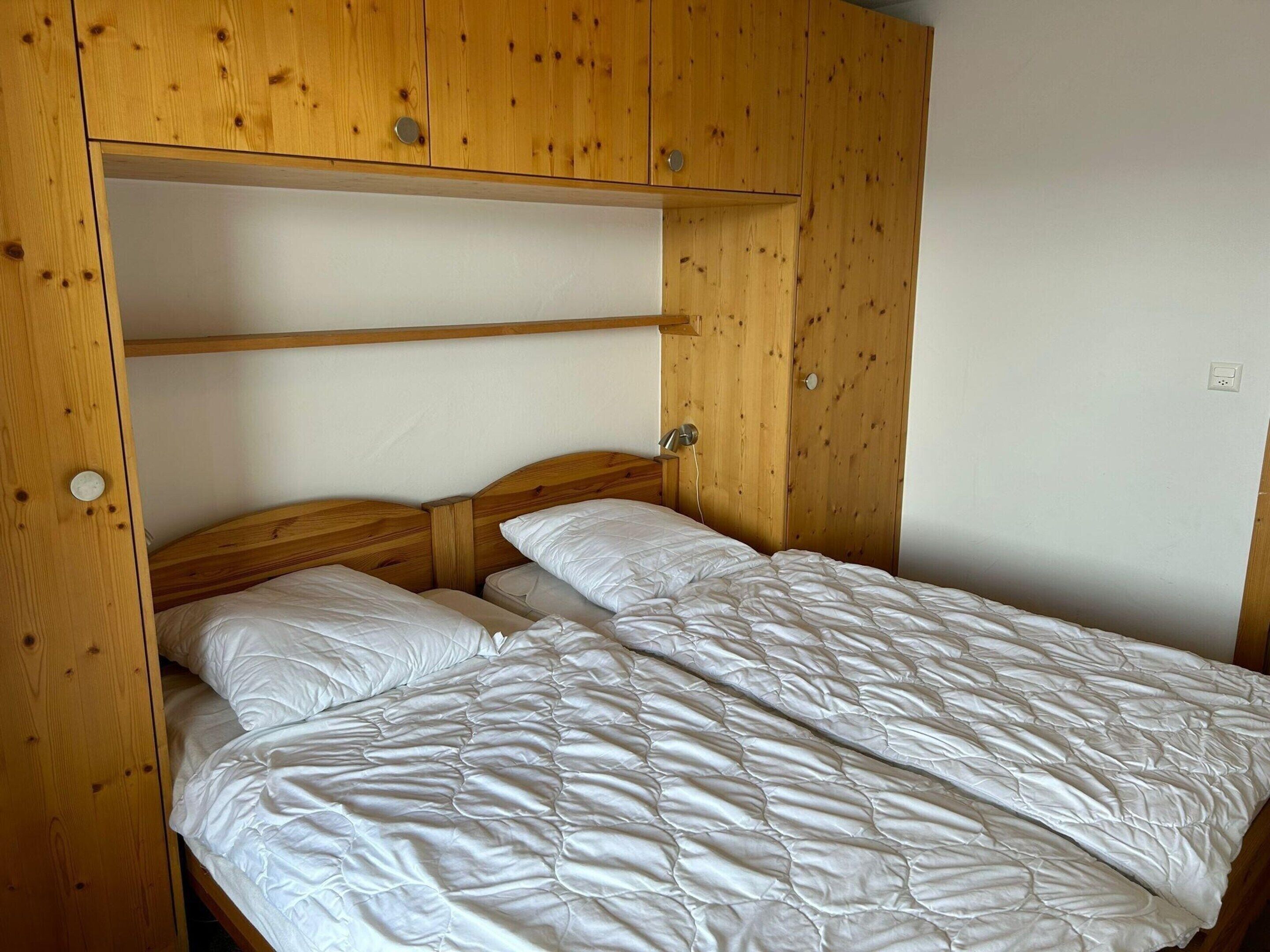 Ein Schlafzimmer mit einem Holzbettgestell und einem Einzelbett, beide mit weißer Bettwäsche.