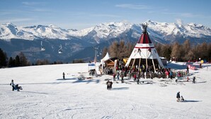 A ski resort with a prominent teepee structure, ski lifts, and a snowy mountain backdrop. - Pleasant Apartment With Balcony (Veysonnaz)