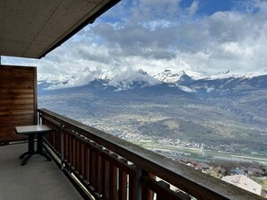 Un balcón con vistas a montañas nevadas y un valle.