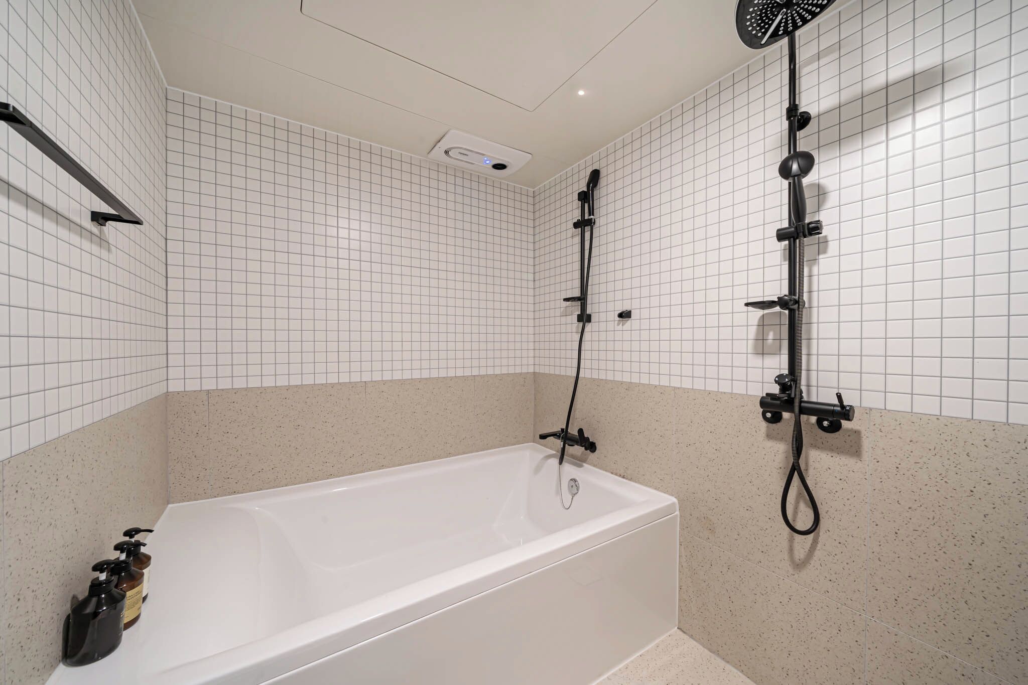 A modern bathroom with a bathtub, a handheld showerhead, and a wall-mounted showerhead.