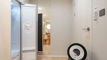 Habitación de hotel con una puerta blanca, una pequeña mesa con sillas y un ventilador de pie.
