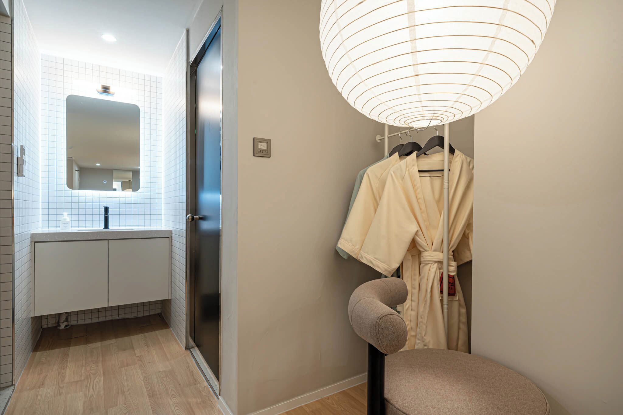 A bathroom with a mirror, sink, and a towel rack with a robe.