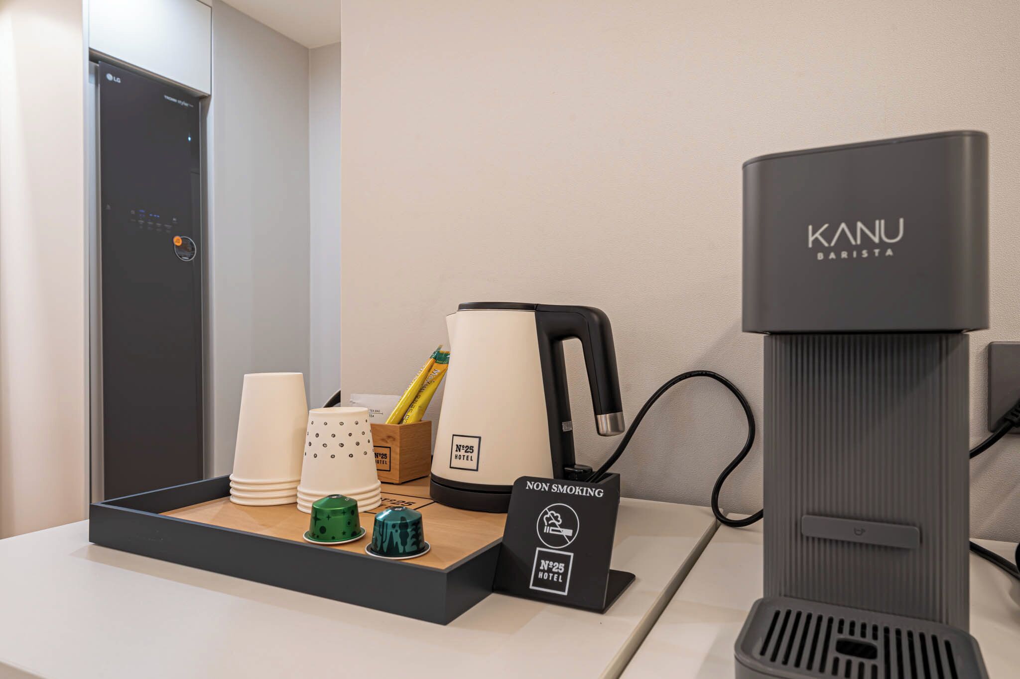 Un minibar de hotel con una máquina barista Kanu, un cartel de prohibido fumar y diversos servicios del hotel.