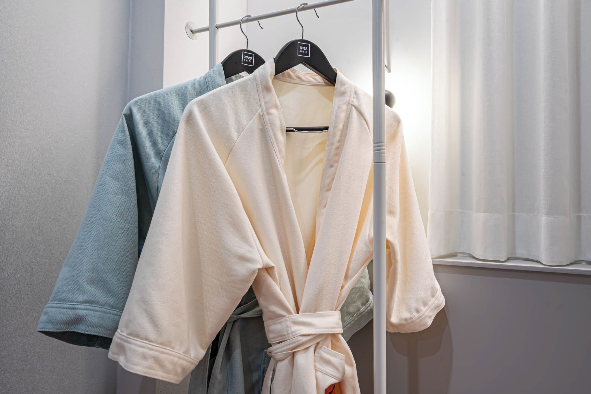 A rack with robes in a neutral color scheme, likely in a hotel or similar accommodation.
