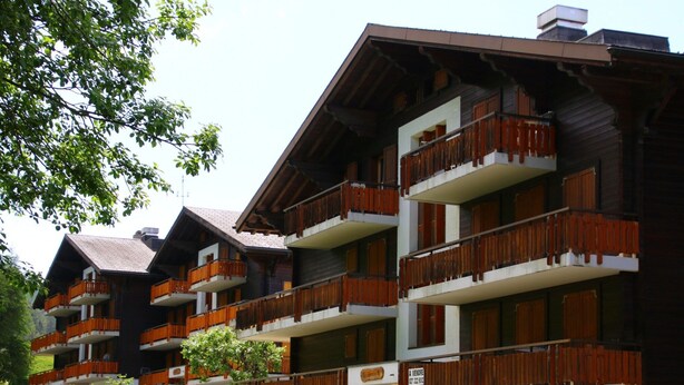 A multi-story hotel with wooden balconies and a stone facade. - Extravagant Apartment With View (Sion)