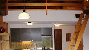 A kitchen with wooden beams, a dining table with chairs, and a staircase. - Extravagant Apartment With View (Sion)