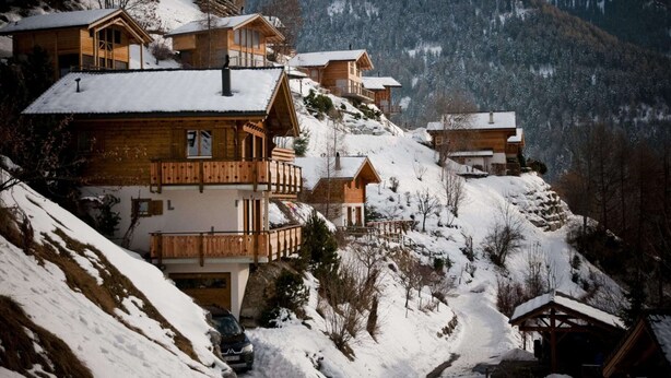 A cluster of wooden mountain cabins with balconies, surrounded by snow-covered slopes and forested hills. - Apartment With Mountain Views (Sion)