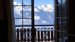 A room with a view of snow-capped mountains through a large window. - Apartment With Mountain Views (Sion)