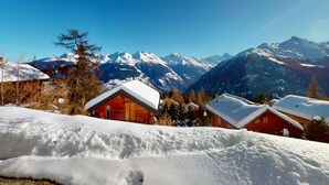 A wooden cabin with a snow-covered roof, surrounded by a snowy landscape and mountains in the background. - Chalet in Thyon-les Collons (Vex)