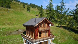 A wooden chalet with a balcony, set on a grassy hillside with a ski lift in the background. - Chalet in Thyon-les Collons (Vex)