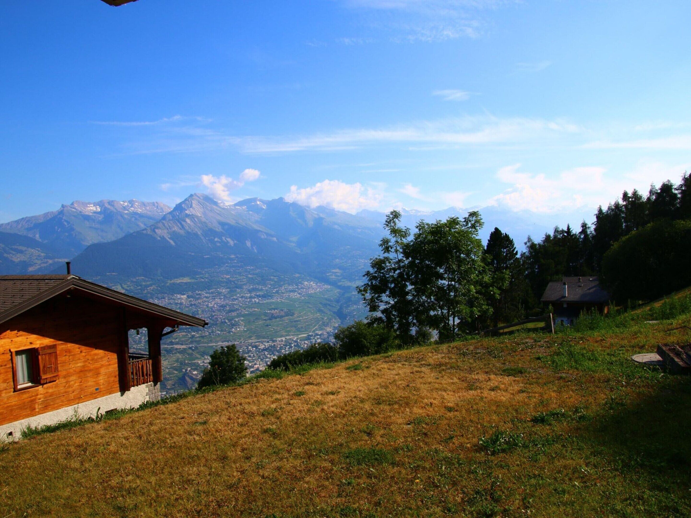 A wooden cabin with a balcony overlooking a mountainous landscape.