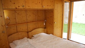 A wooden room with a bed, a window, and a door. - Authentic Apartment With Mountain Views (Veysonnaz)