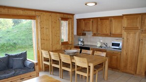 A cozy kitchen with wooden cabinets, a dining table with chairs, a coffee maker, and a microwave. - Authentic Apartment With Mountain Views (Veysonnaz)