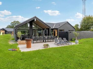 A modern house with a patio, outdoor seating, and a large window. - 5 Star Holiday Home in Dronningmolle (Dronningmolle)
