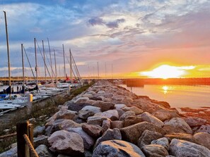 A marina with boats docked along a rocky shoreline during sunset. - 5 Star Holiday Home in Dronningmolle (Dronningmolle)